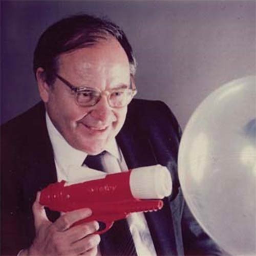 Schawlow shooting at a double balloon with a toy gun that included a real laser. The gun would pop the inside blue balloon but not the clear outer one, showing that lasers could be tuned to pass through a transparent surface.